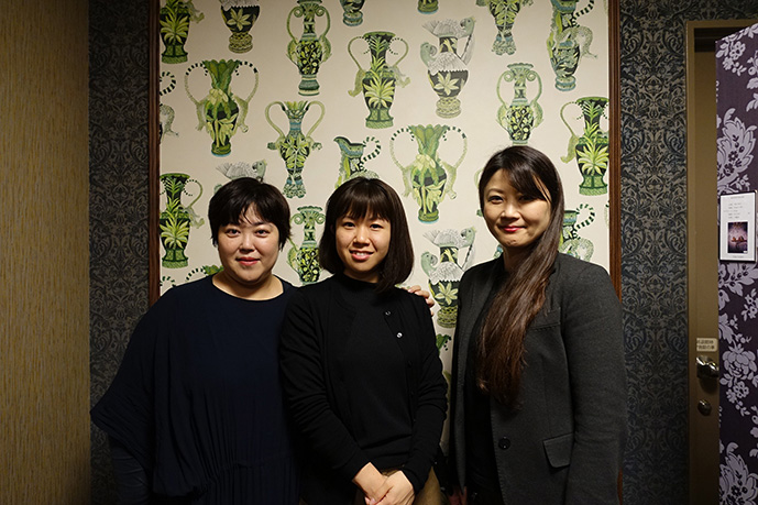 ショールーム入り口のクロスの前にて。受付スタッフ